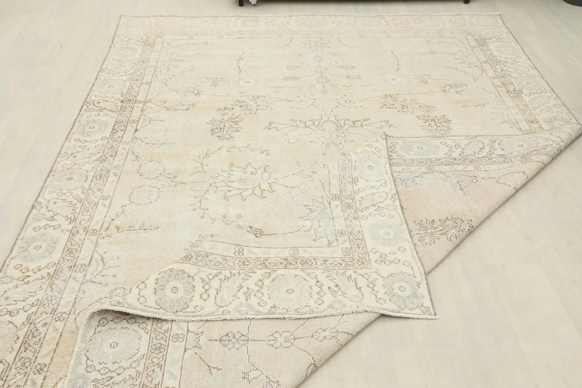 The vintage rug partially folded, revealing the wool pile and cotton foundation.