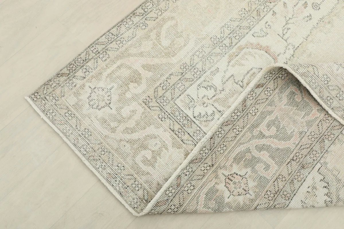 Corner of the Cream Gray Medallion Rug folded to show its thickness and back.