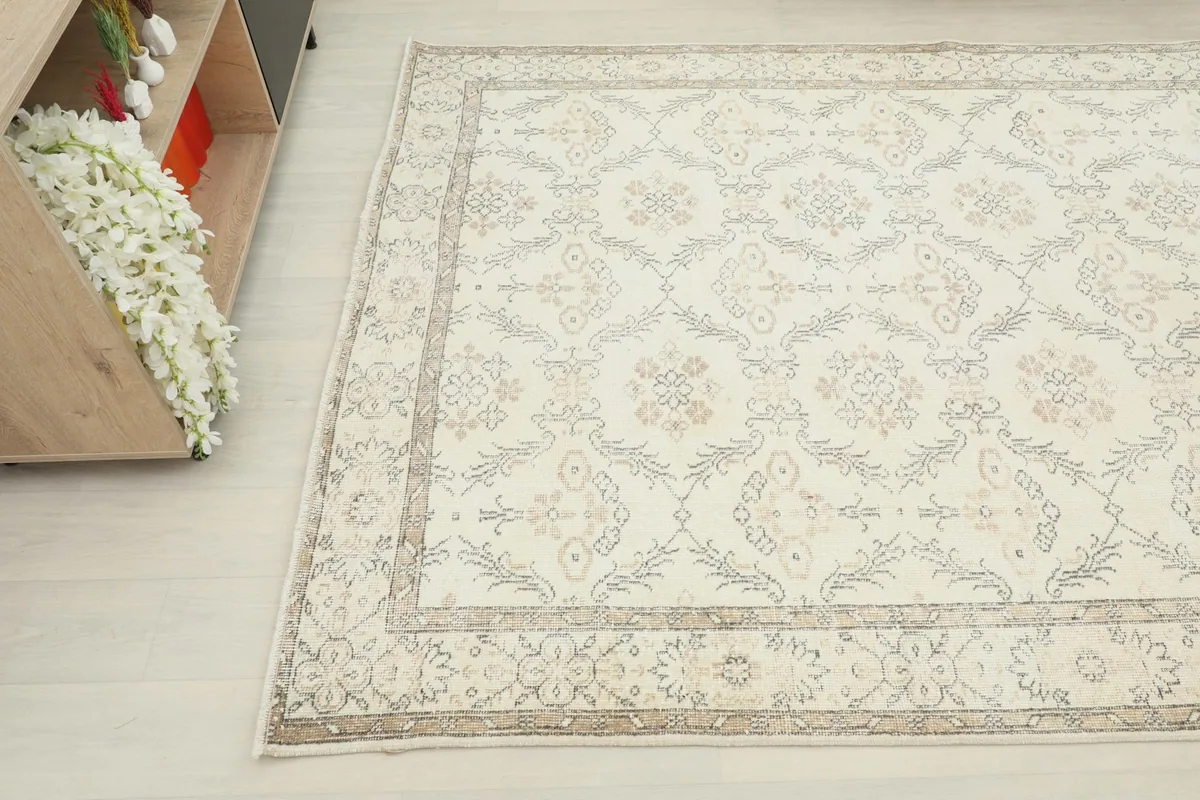 Close-up angle view of the vintage rug, capturing the interplay of cream and tan colors.