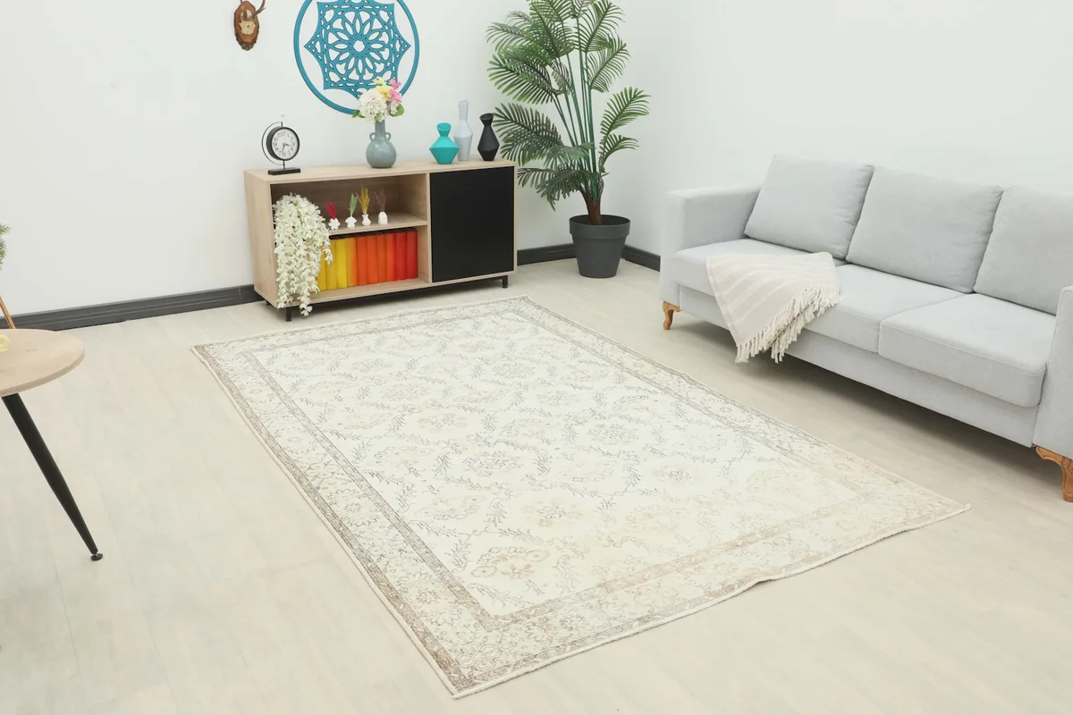 The cream and tan vintage rug placed in a modern living room setting with a light gray sofa.