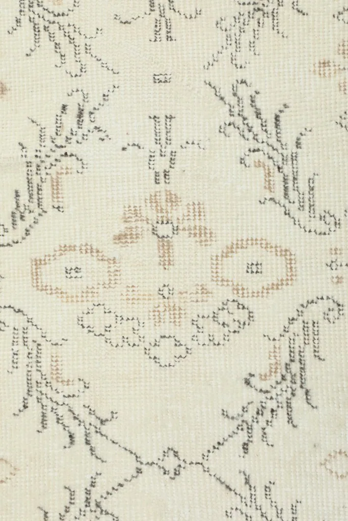 Close-up of the hand-knotted wool pile, showing the detailed beige and gray motifs.