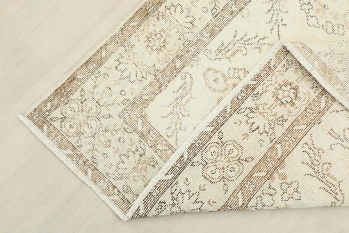 Folded corner of the vintage rug, showing the wool pile and cotton foundation.