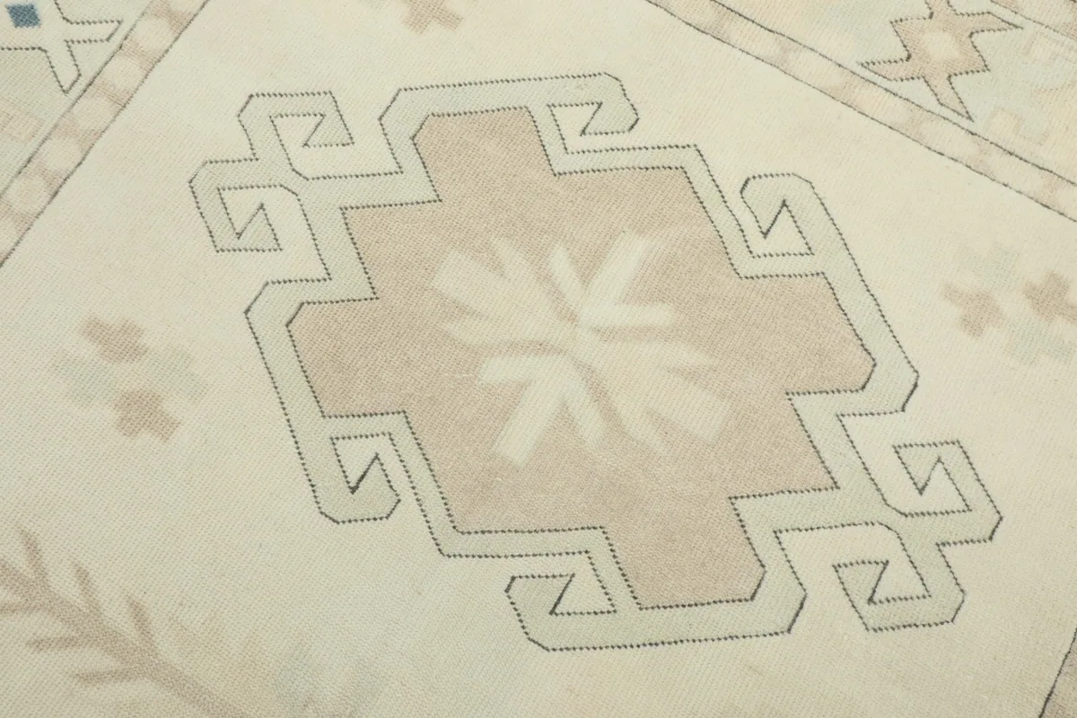 Detailed view of a central tan geometric medallion with intricate patterns on the ivory field