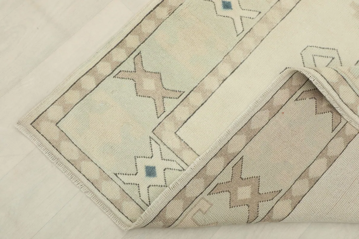 Corner of the rug folded over, revealing the cotton foundation and back of the knots