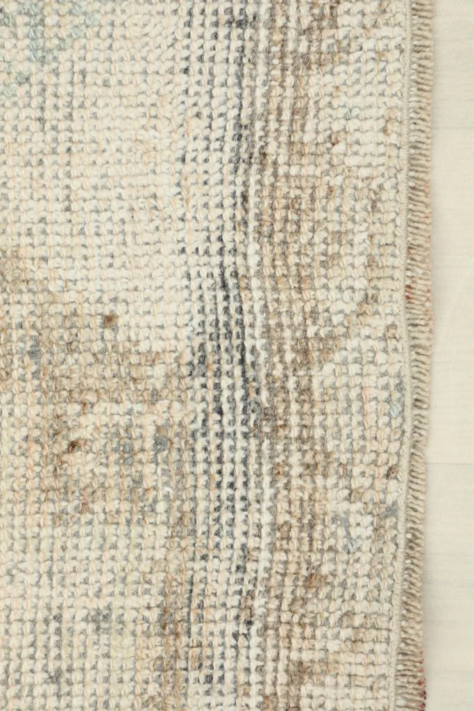 Side view of the rug's low pile, revealing the hand-knotted wool and cotton foundation.