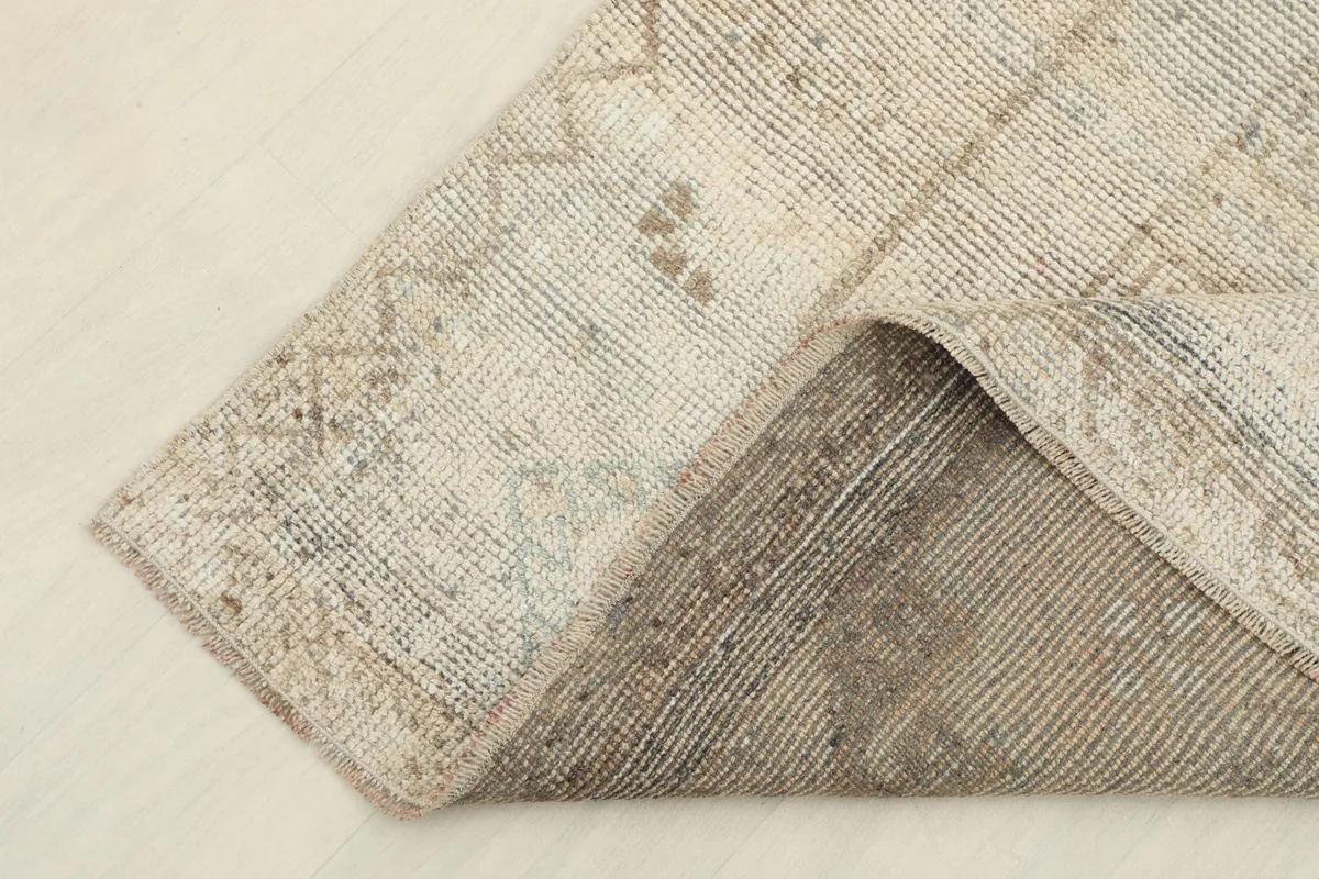 Corner of the rug folded to show the reverse side, highlighting the cotton foundation and knotting.