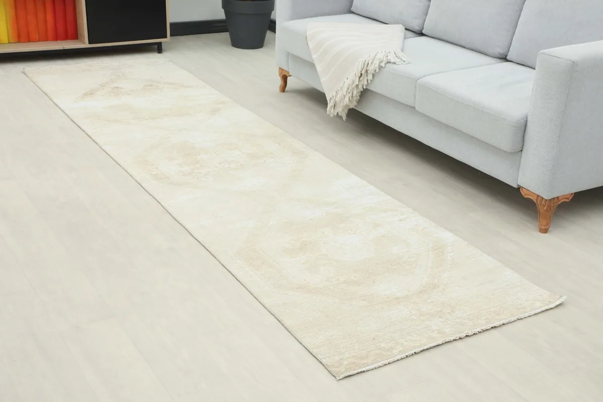 Angle view of the beige runner rug extending along a light-colored floor next to a sofa.