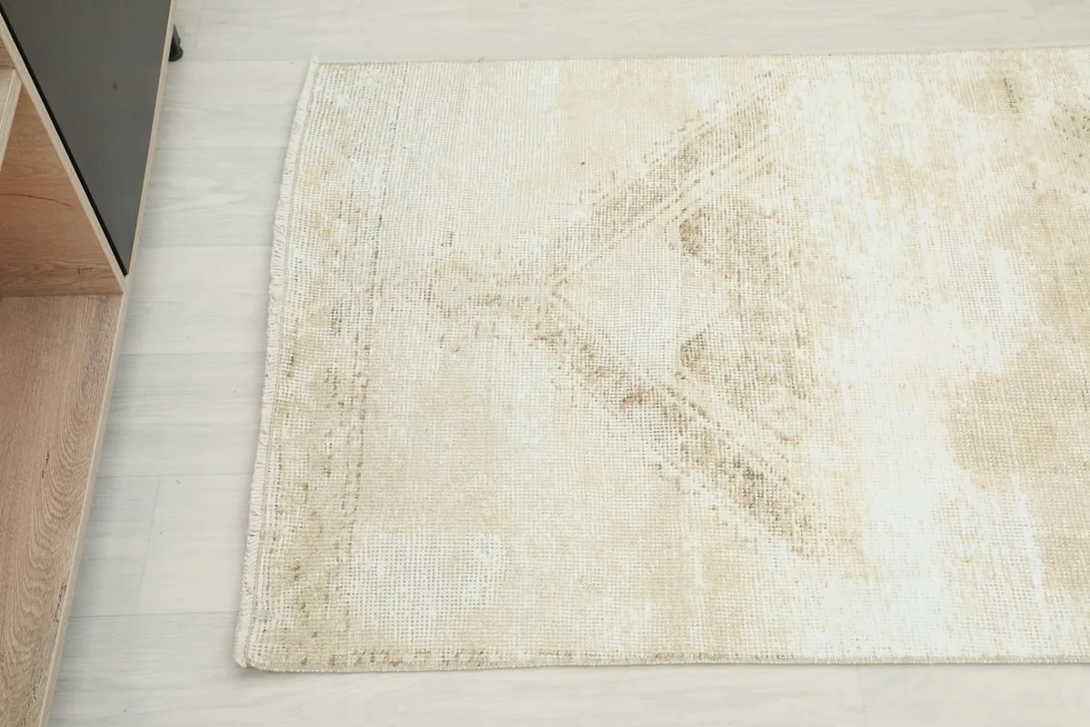 Detail shot showing the faded geometric pattern and natural wear on one end of the beige runner.