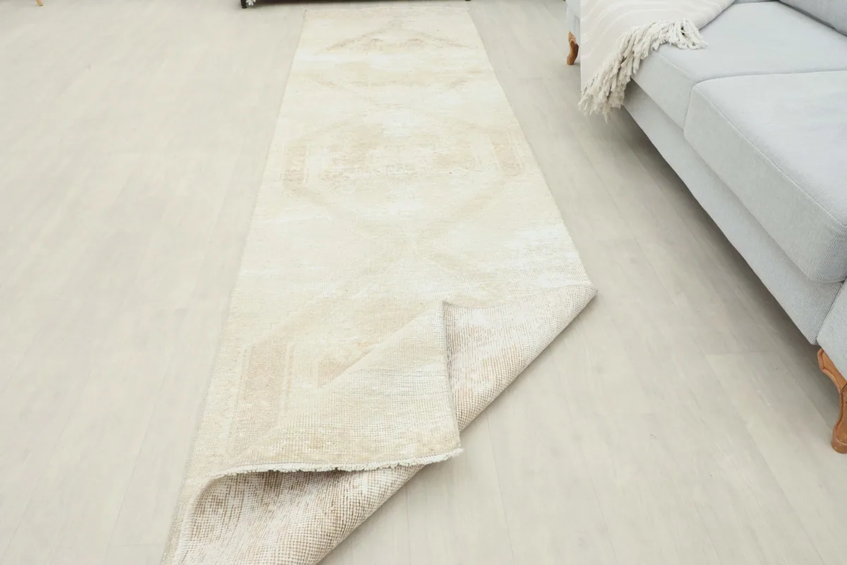 Runner rug partially folded, showcasing its flexibility and the consistent beige tone.