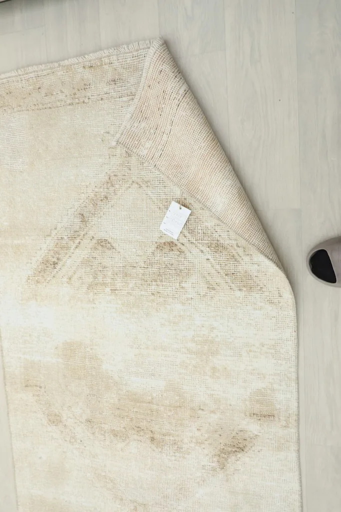 Underside of the rug with a tag, showing the cotton foundation and fine hand-knotting.