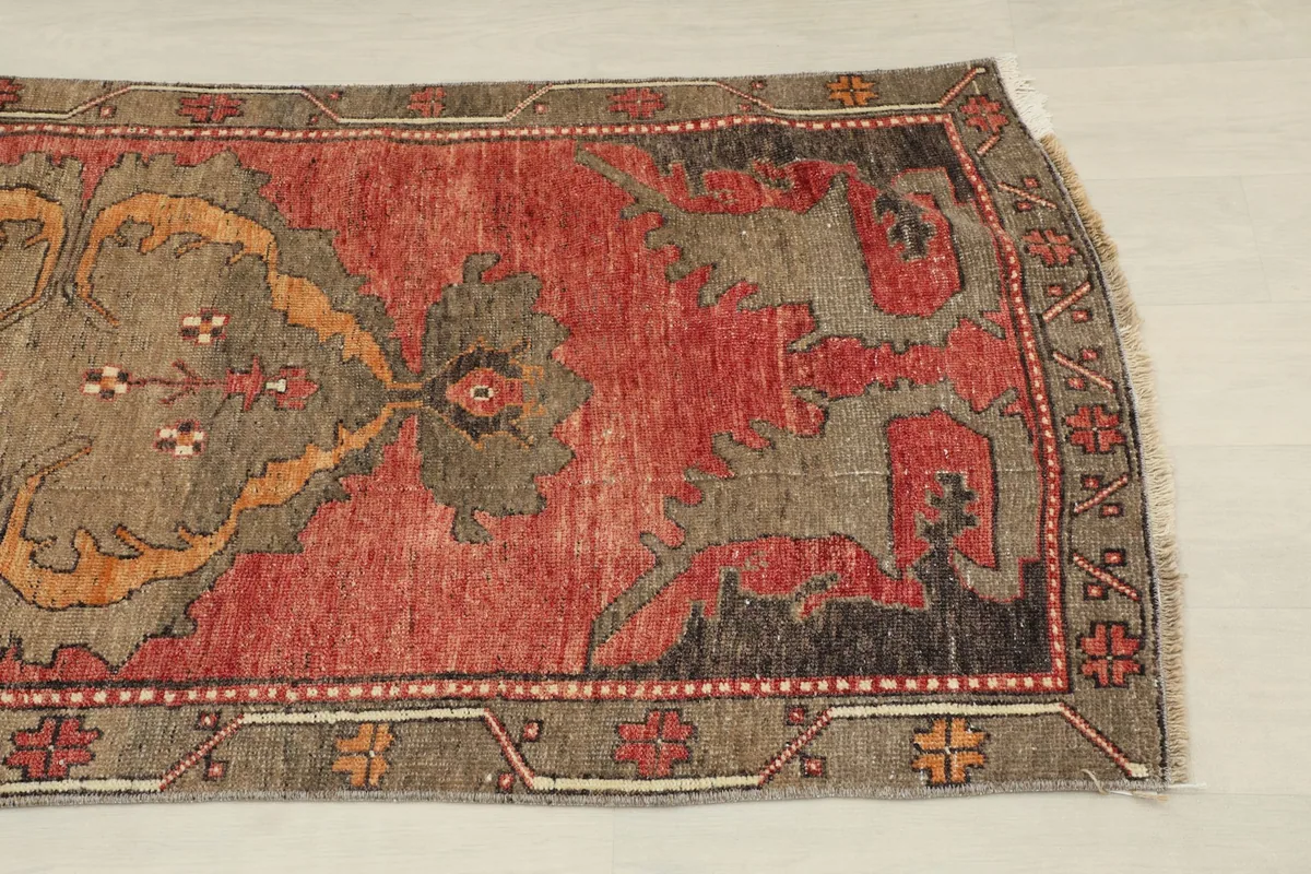 Close-up view of the lower half of the rust runner rug, showing tribal motifs and border design
