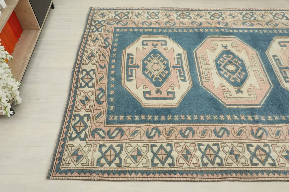 Angled view of the blue and rose vintage rug with part of furniture visible