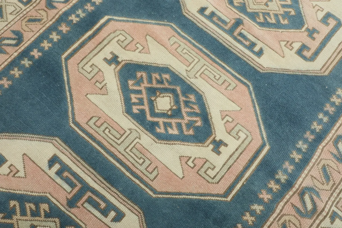 Close-up of a central rose and ivory geometric medallion on the blue field