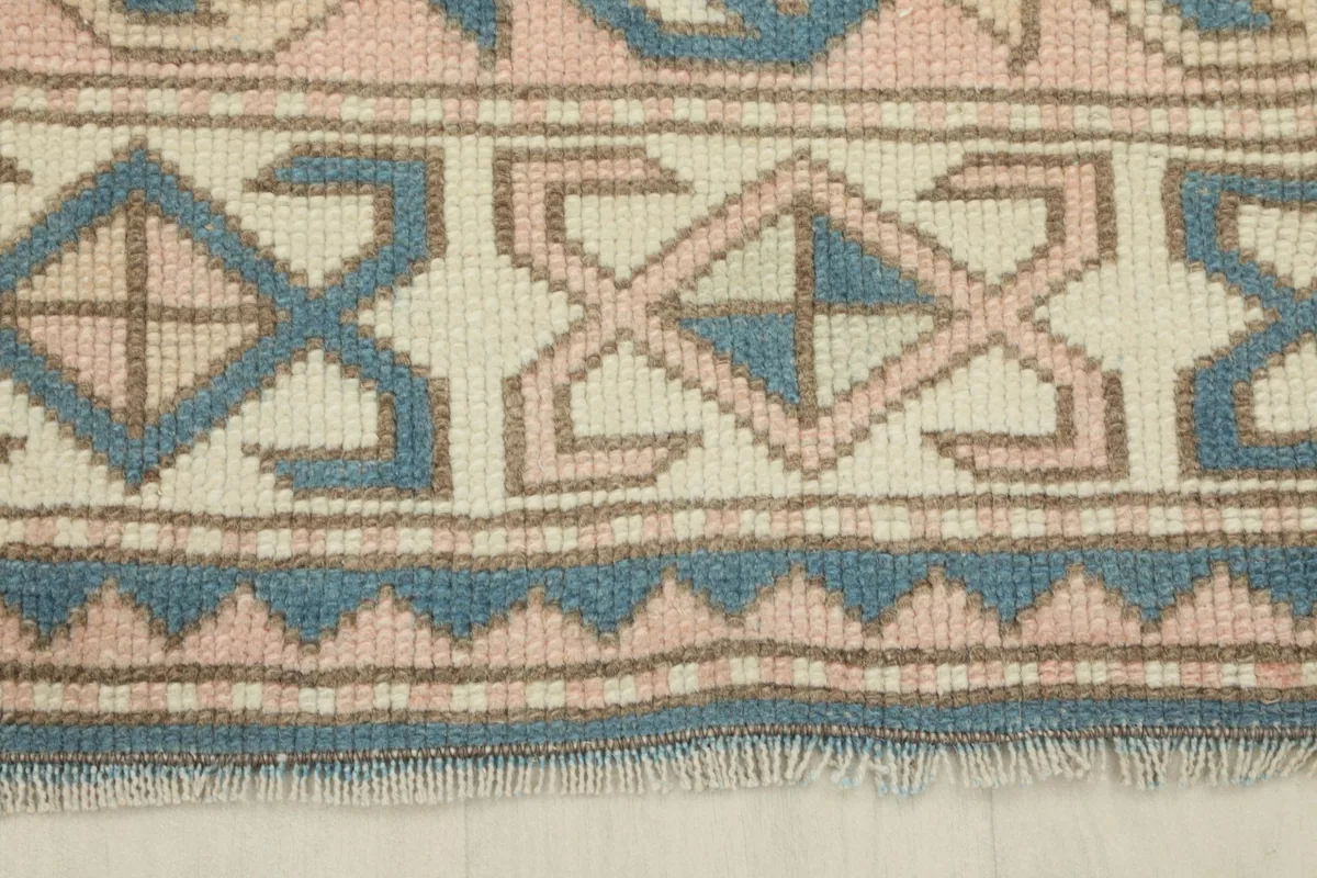 Close-up of the rug's border with intricate blue, rose, and ivory patterns
