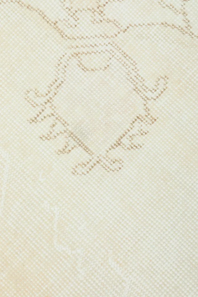 Close-up of a central geometric design element within the ivory rug's field.