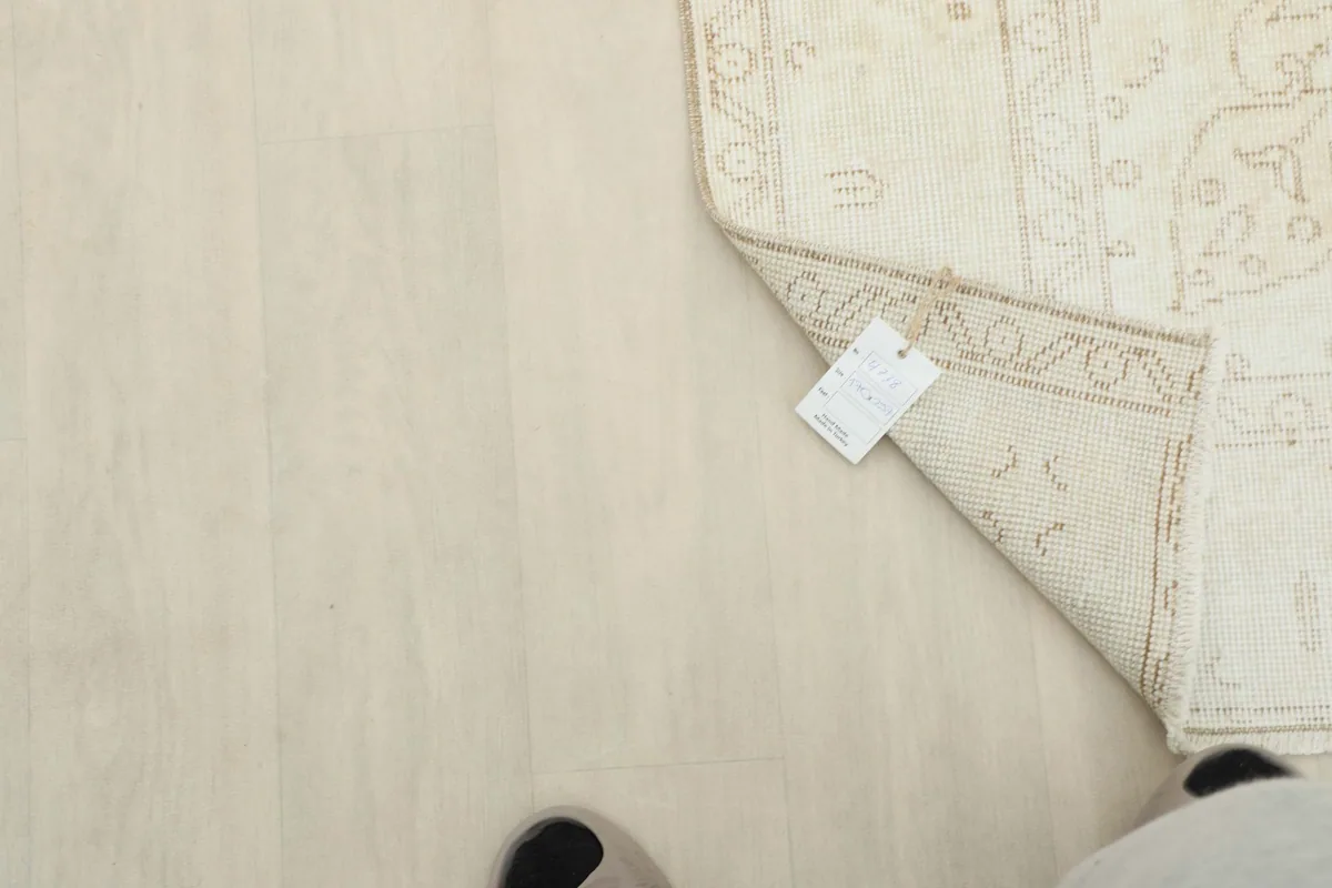 Overhead view of a corner of the rug with a tag, demonstrating its size relative to feet.