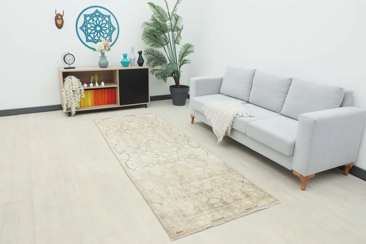 Runner rug placed in a modern living room setting, showing its long shape next to a sofa.