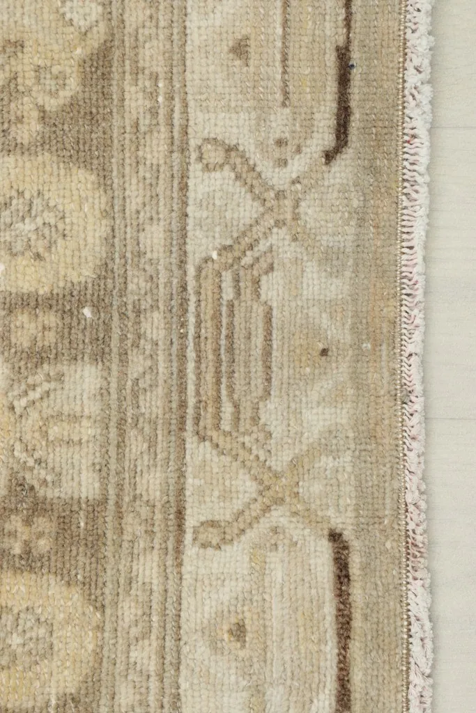 Close-up of the rug's side border, showcasing the geometric design and fringe.
