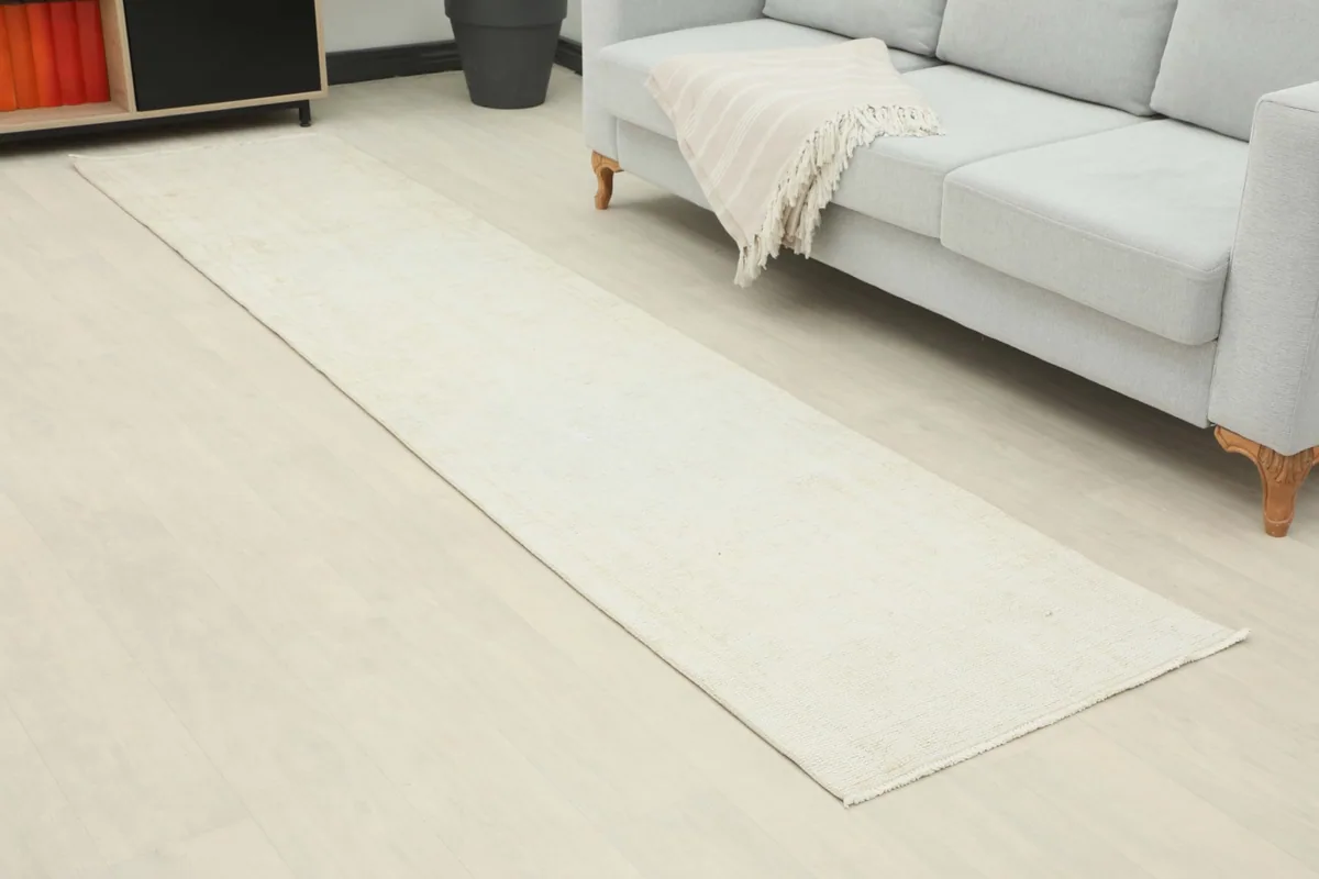 Angled view of the ivory runner rug laid out in a room, showing its length and subtle texture.