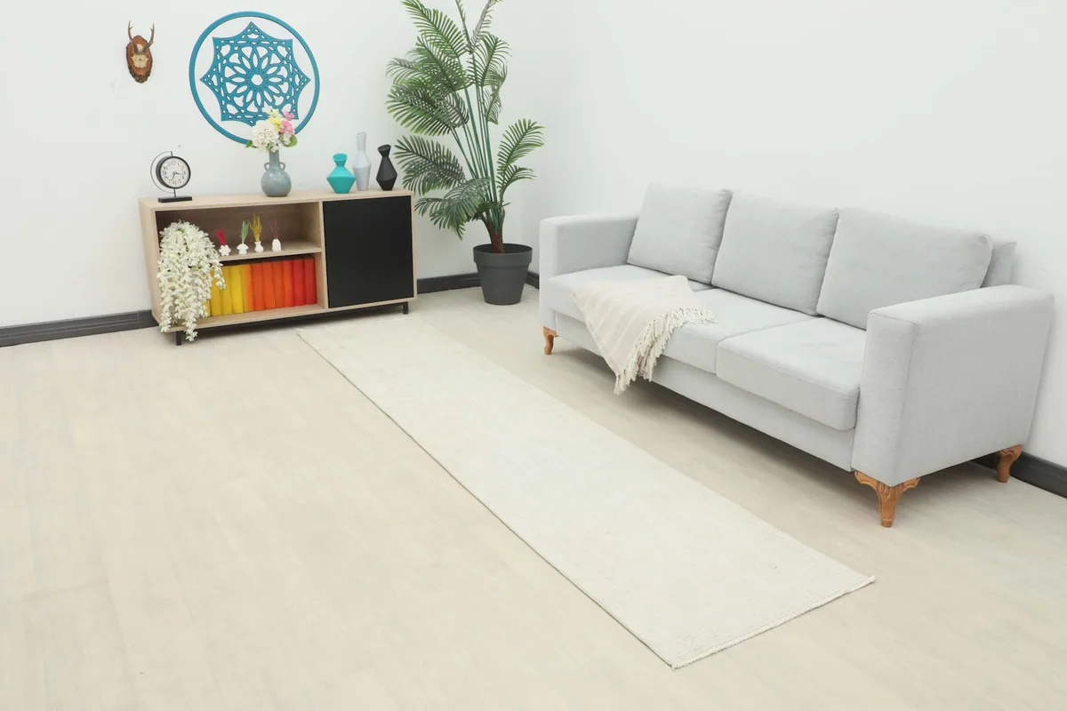 Ivory runner rug in a modern living room setting, extending from a light gray sofa.