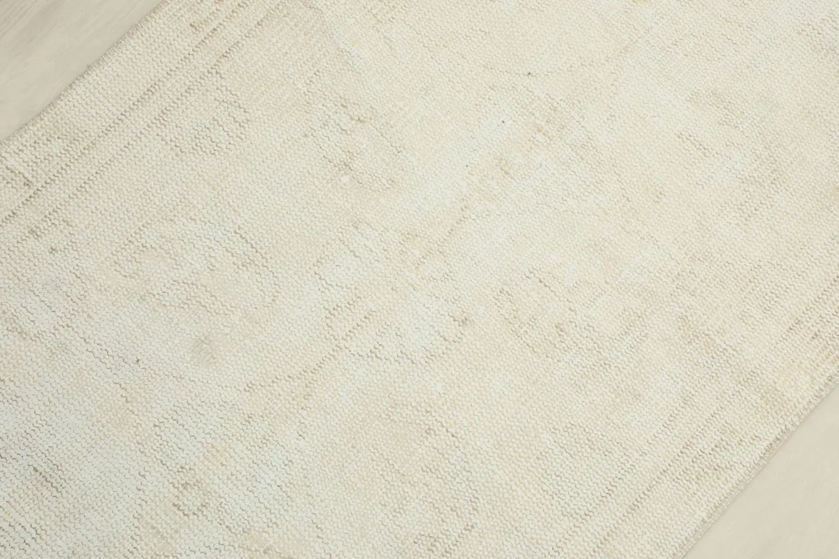 Mid-section close-up of the ivory runner, revealing subtle geometric motifs woven into the wool pile.