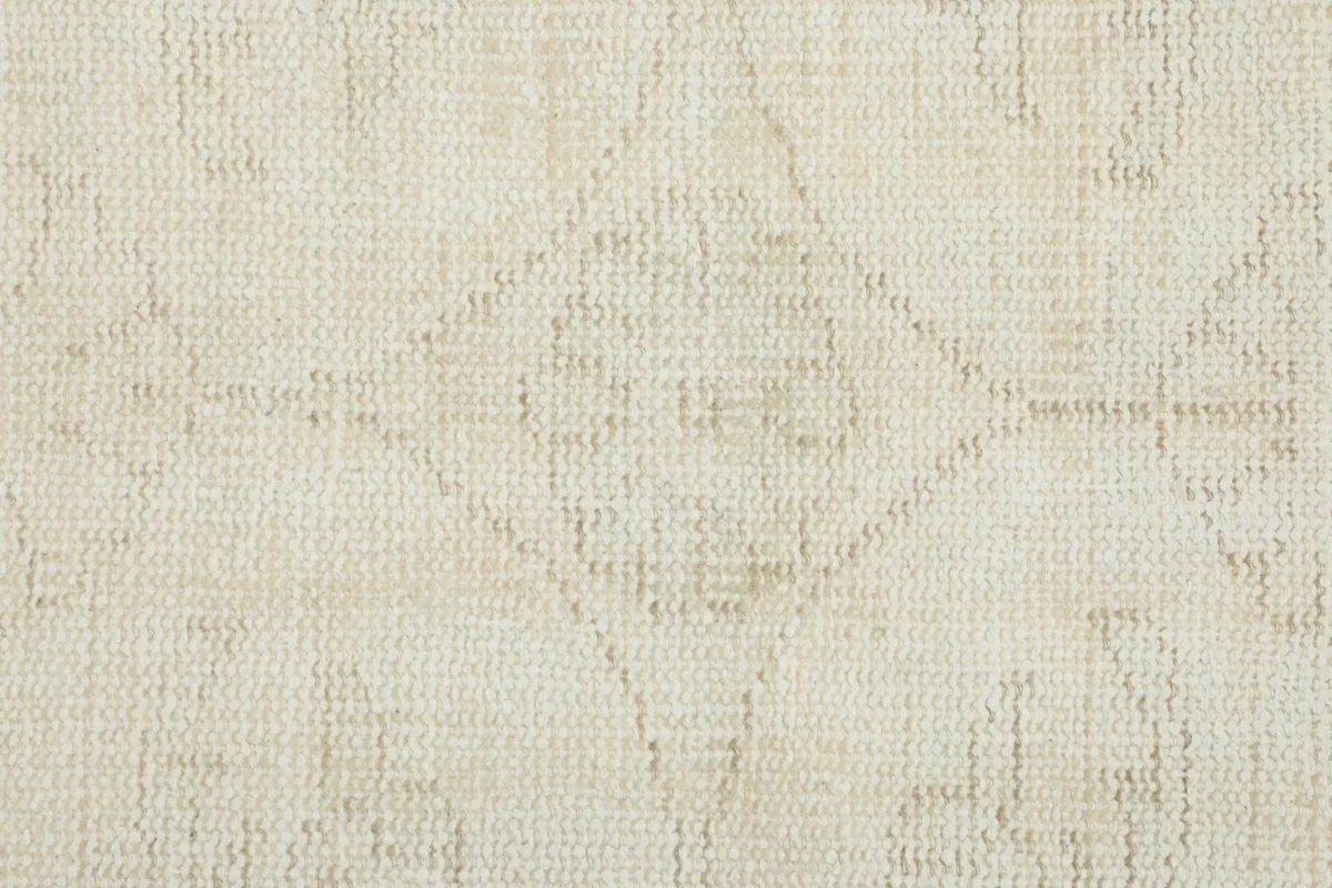 Detailed view of the low wool pile, showcasing the hand-knotted texture and a faded diamond pattern.