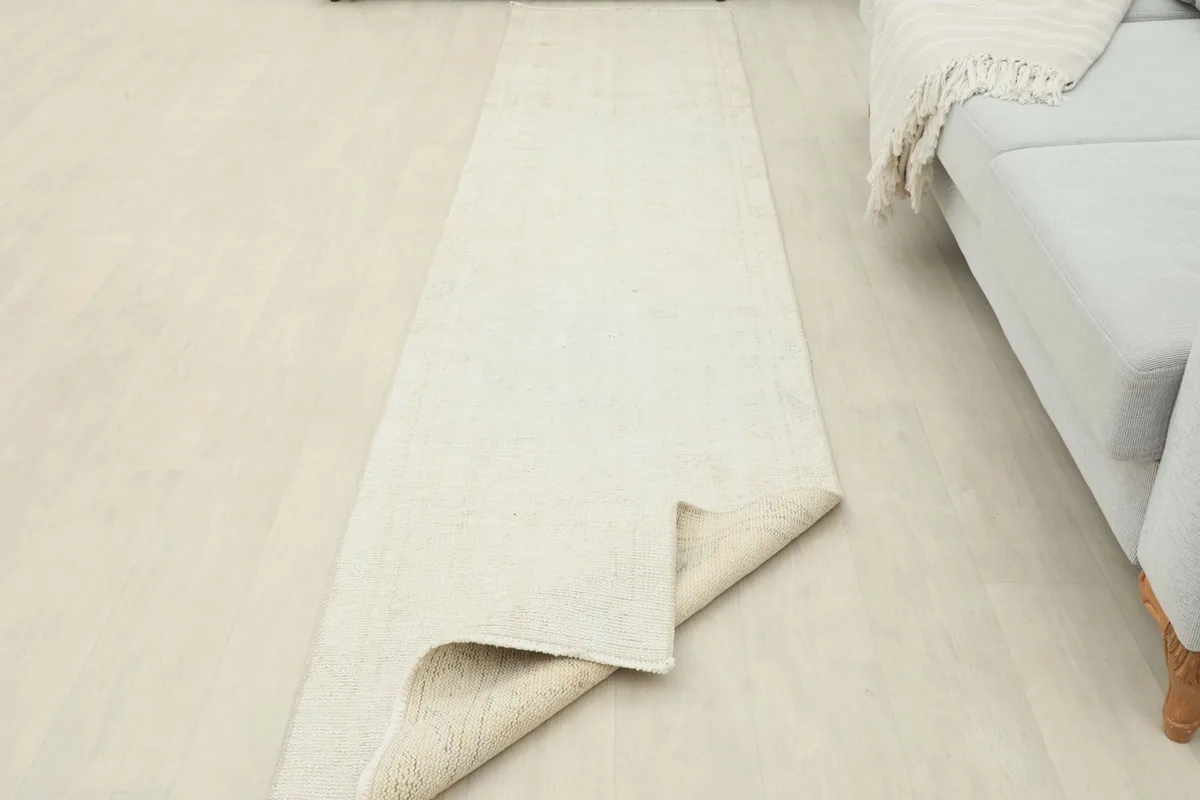 The ivory runner partially folded, demonstrating its flexibility and the thickness of the wool pile.