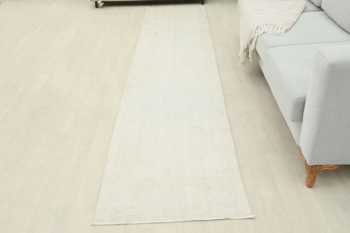 Overhead view of the ivory runner extending across the floor next to a light gray sofa in a room setting.