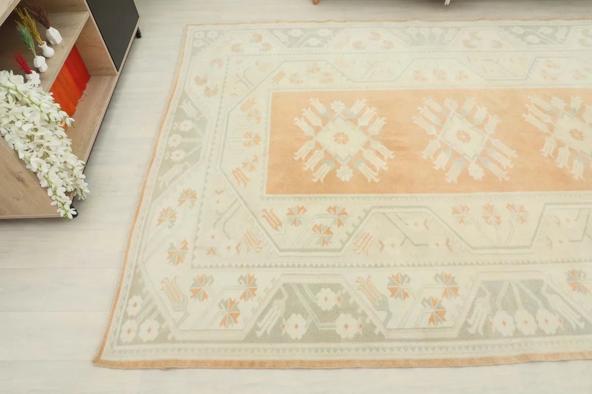 Overhead view showing a section of the rug's border and central orange field with motifs.