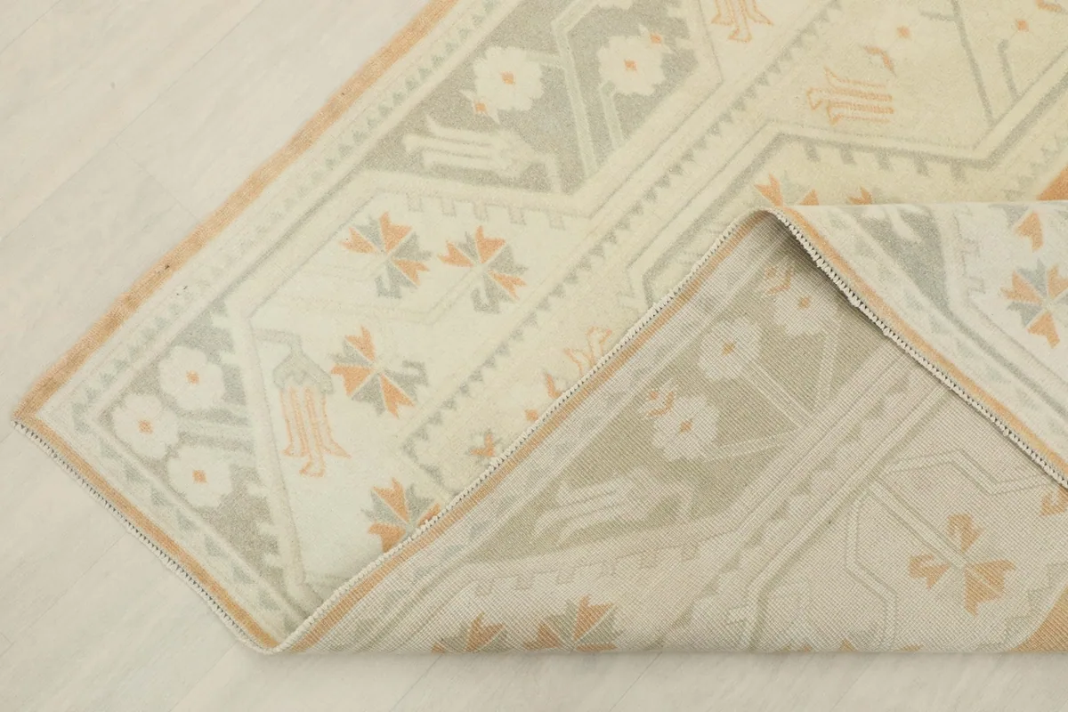 Corner of the rug folded back, revealing the reverse side and the hand-knotted construction.