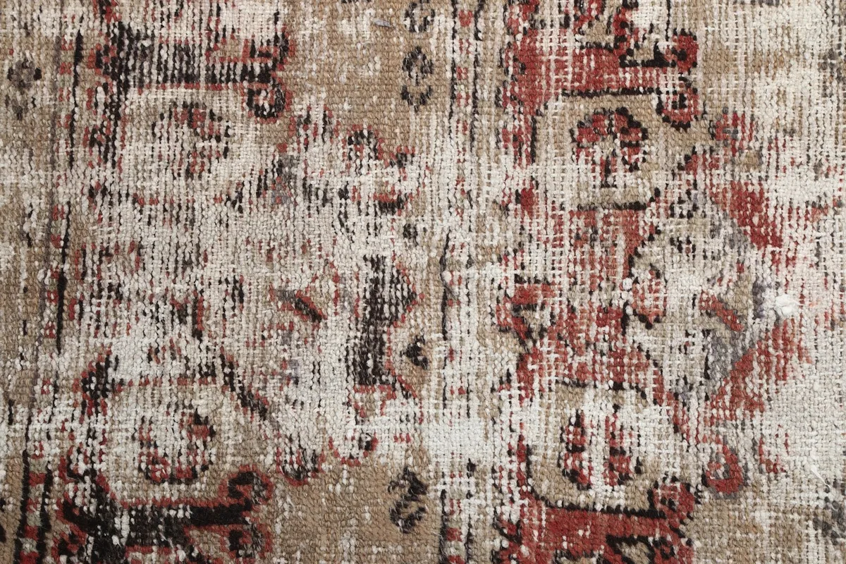 Close-up of the rug texture and worn patterns, revealing cream undertones from age.