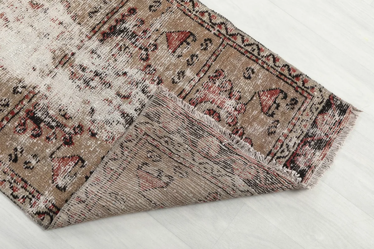 Folded corner of the rug, showing the thickness of the hand-knotted wool pile and cotton foundation.