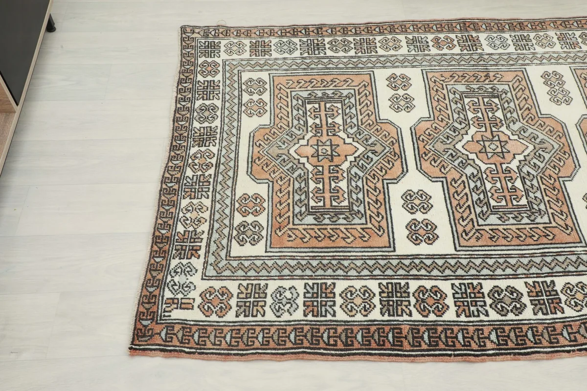 Close-up angled view of the rug's patterns, highlighting the rust and gray colors