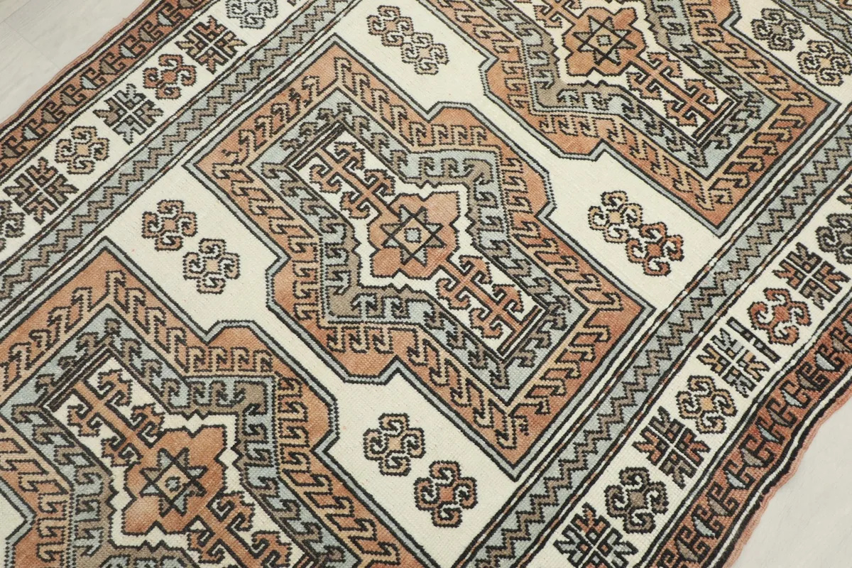 Detailed view of the central geometric medallion and surrounding tribal motifs in ivory, rust, and gray