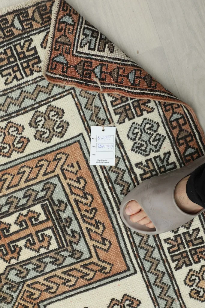 Close-up of the rug's low wool pile next to a foot, showing texture and authentic wear