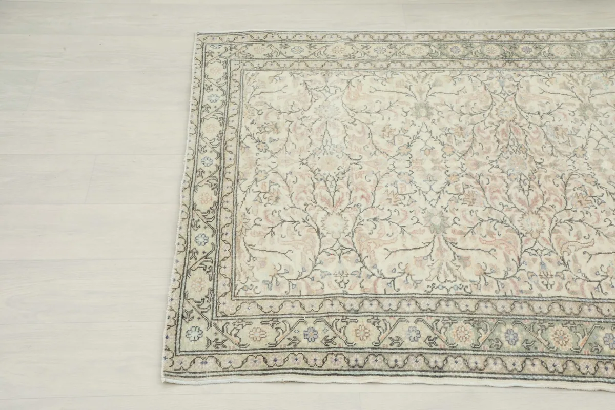 Diagonal view highlighting the intricate green border and ivory field of the Anatolian rug