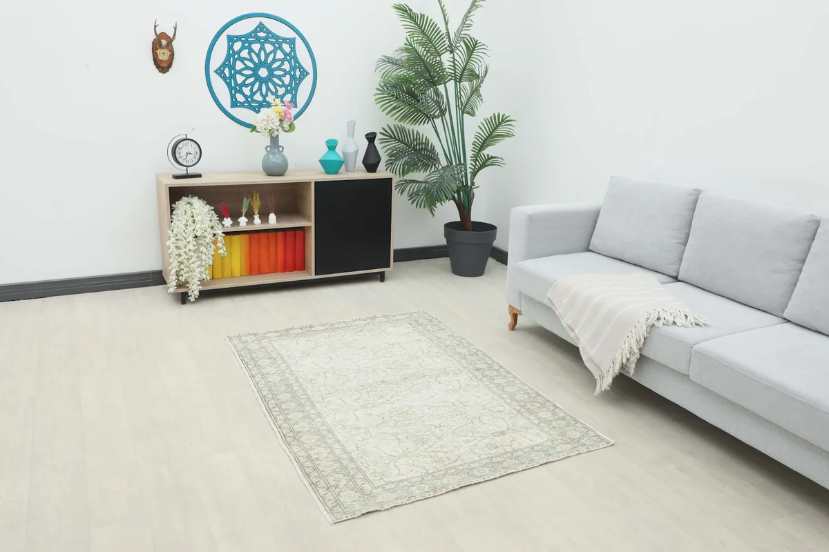 Ivory and rose vintage rug styled in a modern living room setting with a gray sofa