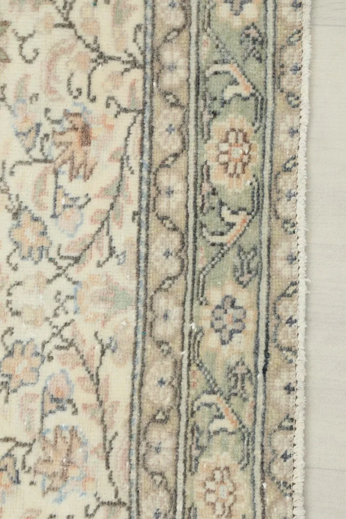 Close-up of the decorative green border with subtle floral designs and the rug's edge