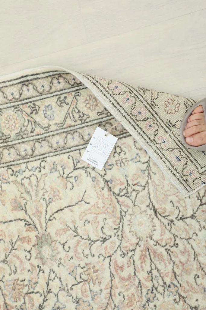 View of the rug's back, displaying the hand-knotted construction and a product tag
