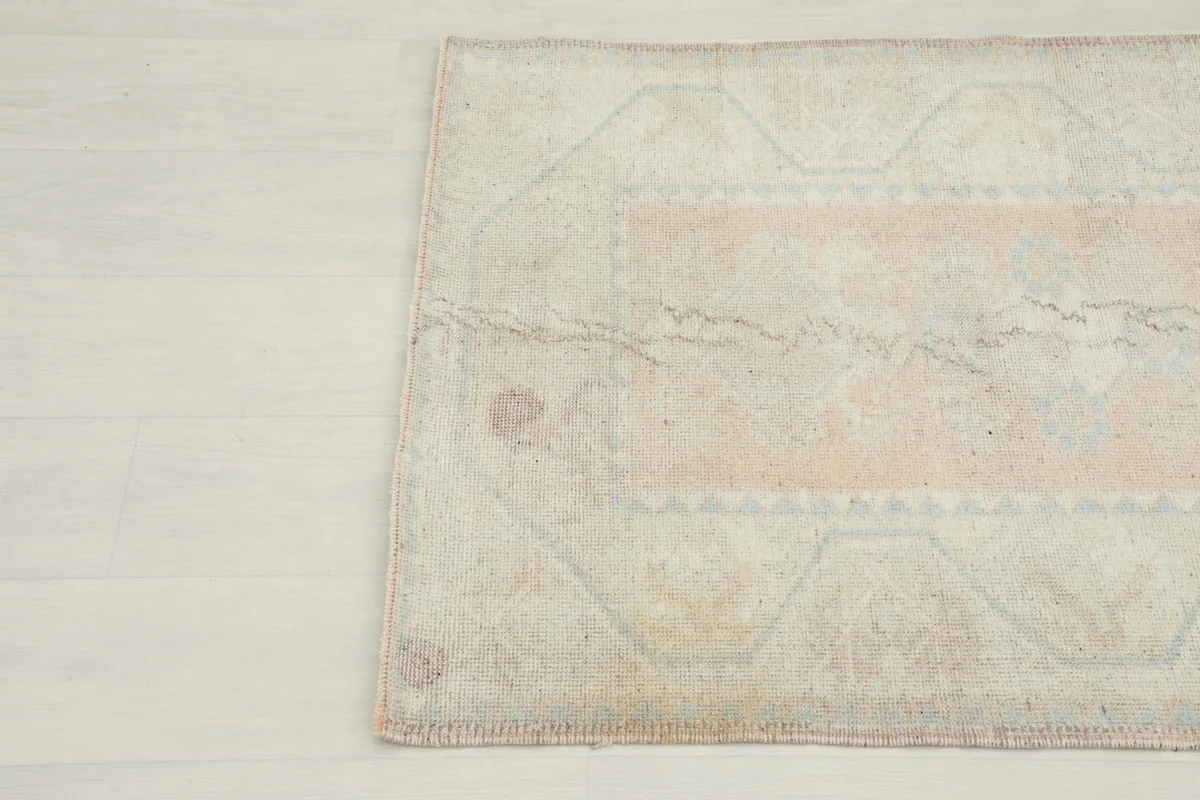 Close-up of the bottom left section of the rug, showing the worn pile and color variations