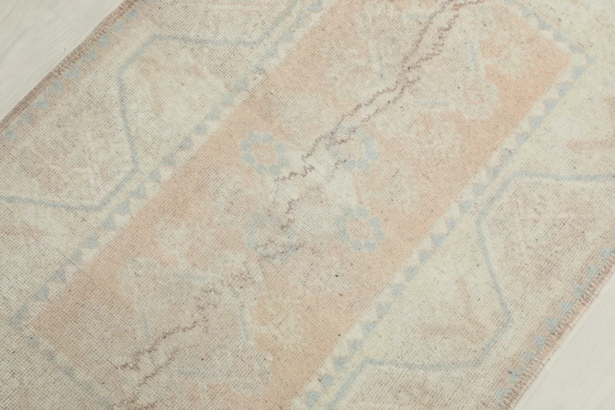 Detailed view of the central rose field and faded blue geometric motifs within the rug