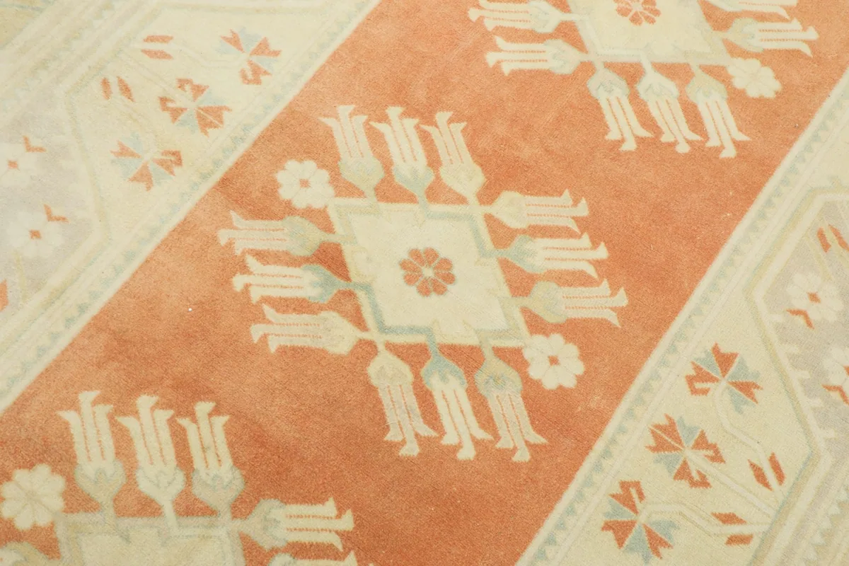 Detailed view of the central rust field with cream floral medallion patterns.