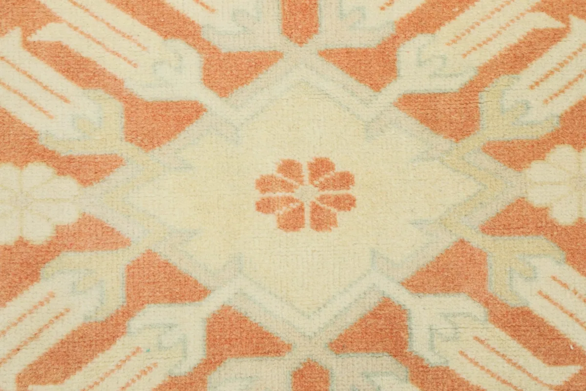 Close-up of a single cream medallion motif with a small rust flower at its center.