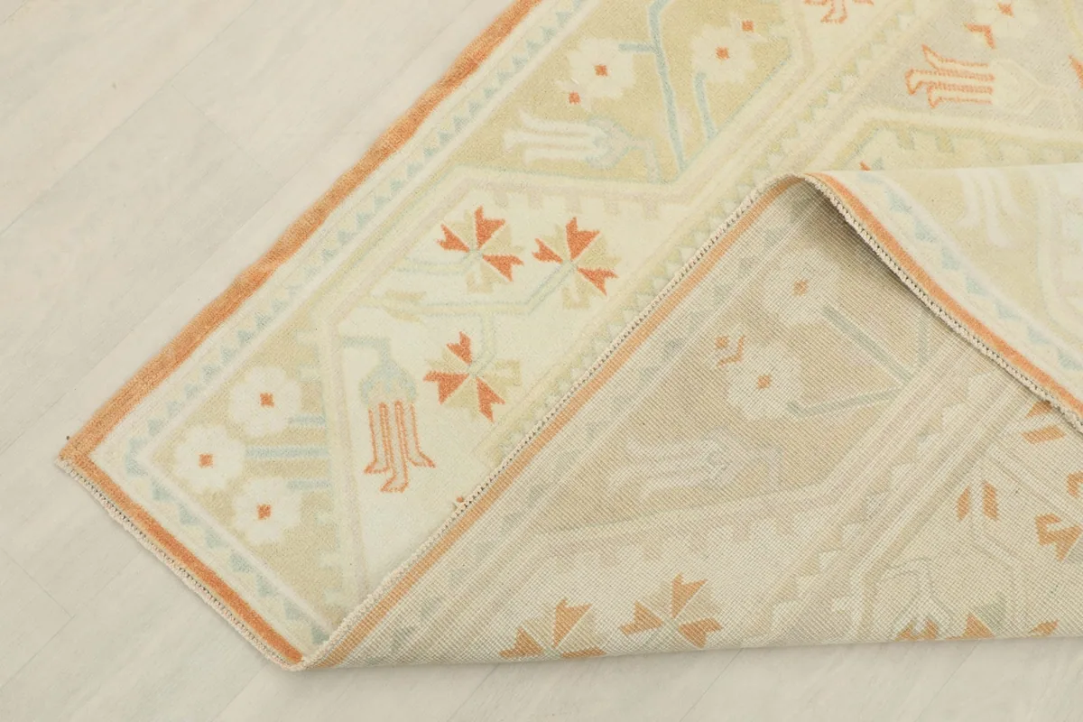 Corner of the rug folded back, revealing the cotton foundation and the reverse side of the knots.
