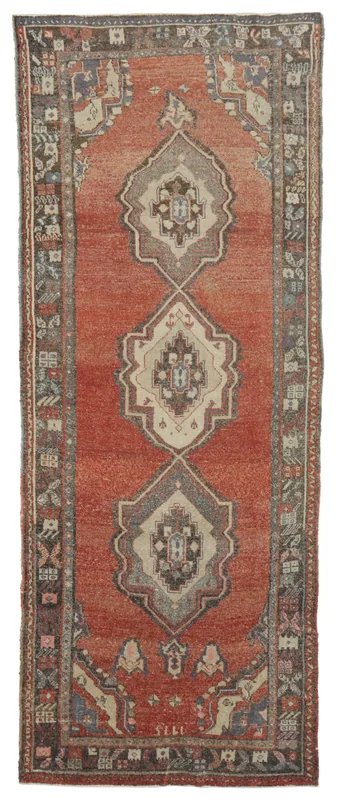 Full top view of the vintage rust Anatolian runner rug with geometric medallions on a white background.