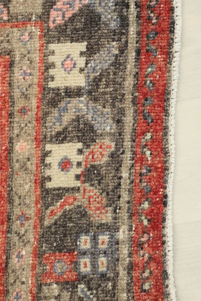 Close-up of the rug's side border, displaying the varied geometric patterns and colors.