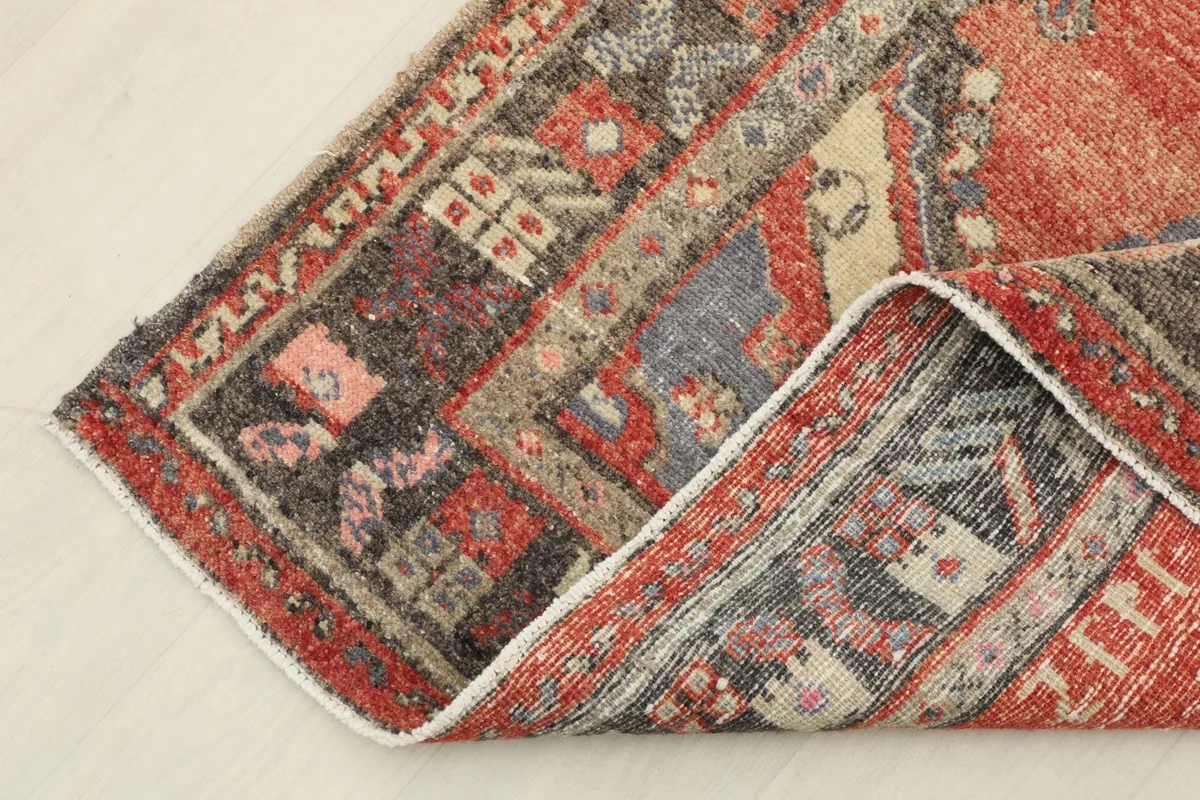 Corner of the rug folded back, revealing the hand-knotted wool pile and cotton foundation.