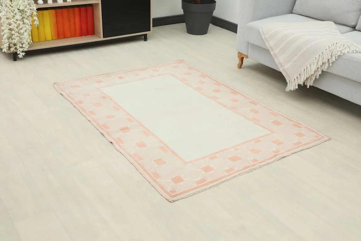 Angled view of the ivory and rose vintage Anatolian rug on a light wood floor