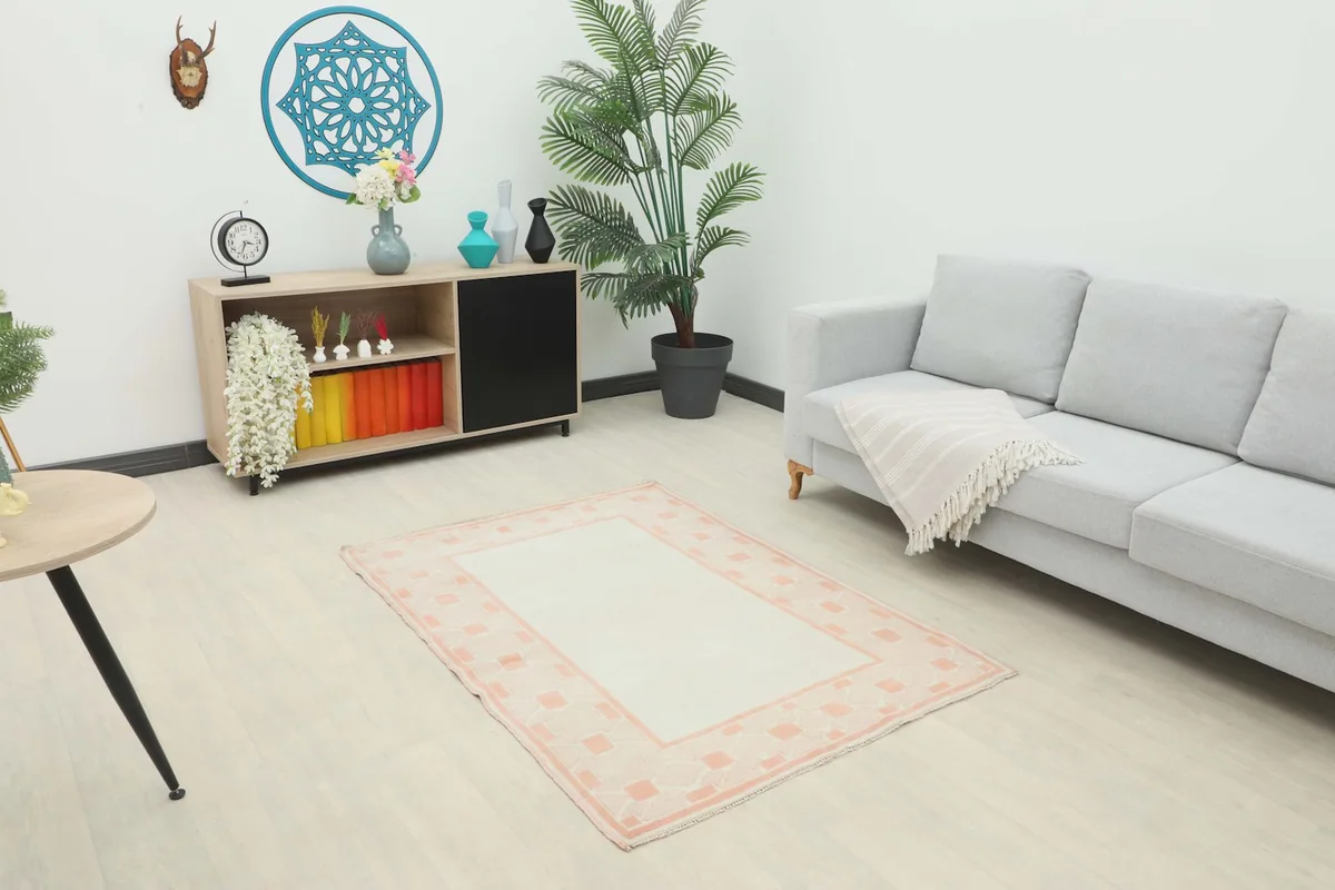 Oversized ivory and rose geometric Anatolian rug in a minimalist living room setting