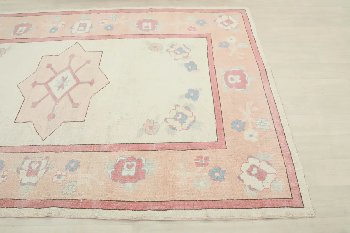 Close-up angle of the rug, detailing the rose border with floral motifs and ivory field